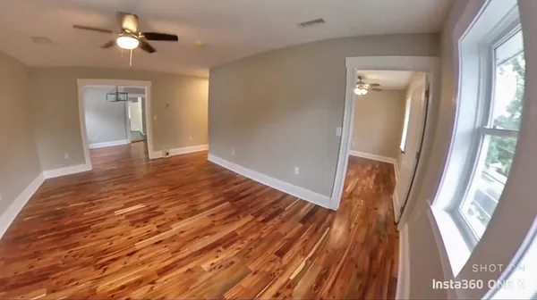 a view of empty room with wooden floor and fan