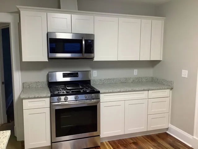 a kitchen with stainless steel appliances granite countertop grey cabinets and a stove top oven