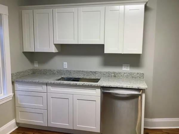 a kitchen with granite countertop white cabinets and a stove