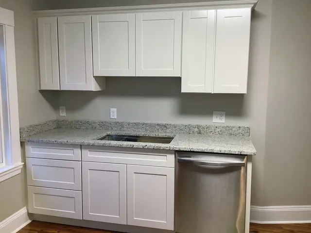 a kitchen with granite countertop white cabinets and a stove