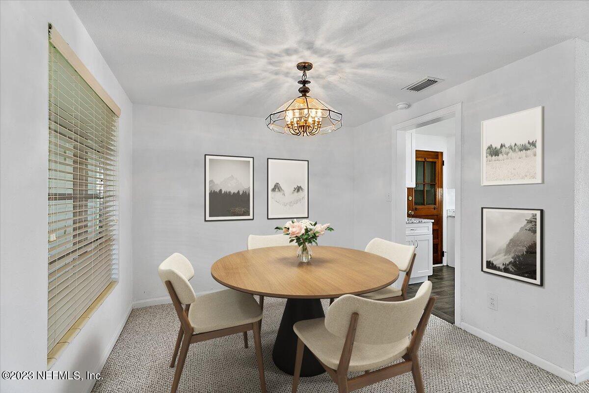 8543 Synhoff Drive Jacksonville, FL 32216 - Photo 6 of 19 a dining room with wooden floor a chandelier a glass table and chairs
