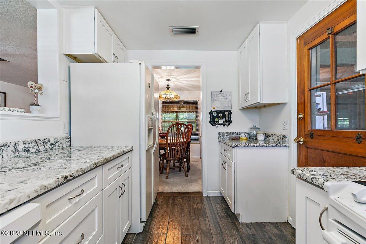 8543 Synhoff Drive Jacksonville, FL 32216 - Photo 9 of 19 a kitchen with a refrigerator a stove top oven a sink and dishwasher with wooden floor