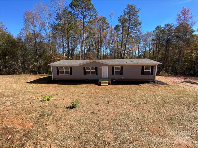 a view of house with outdoor space and trees in the background