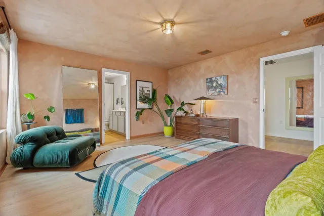 a bedroom with a bed couches and a flat tv screen