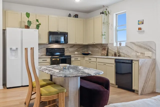 a kitchen with stainless steel appliances granite countertop a white cabinets and a refrigerator