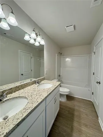 a spacious bathroom with a granite countertop sink a toilet and a bathtub