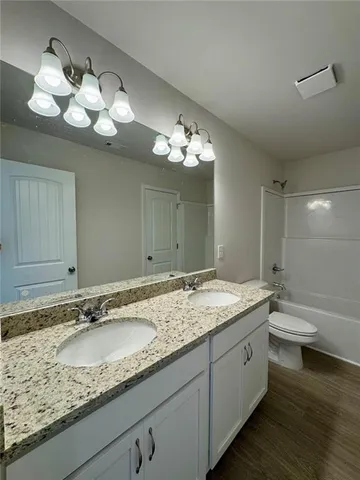 a bathroom with a granite countertop sink a toilet and a large mirror