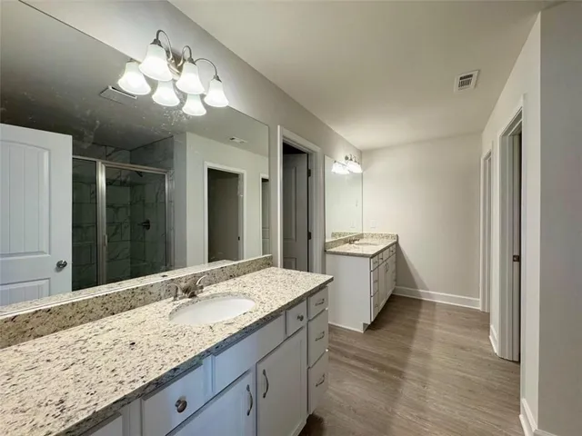 a bathroom with a granite countertop double vanity sink and a mirror
