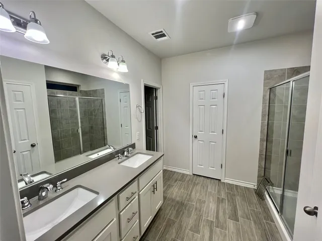 a bathroom with a double vanity sink and mirror with shower