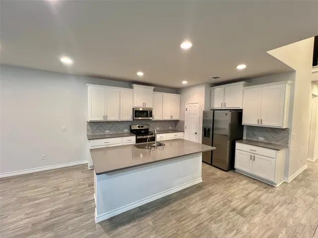 a large kitchen with kitchen island a sink a stove a refrigerator and a center island