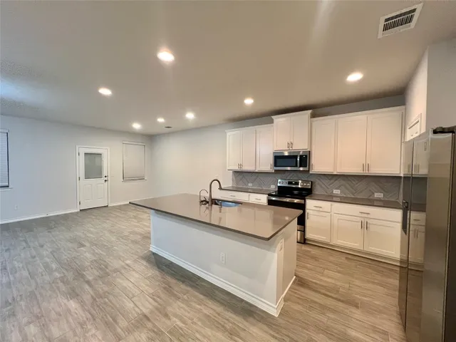 a kitchen with stainless steel appliances granite countertop a stove a sink and a refrigerator