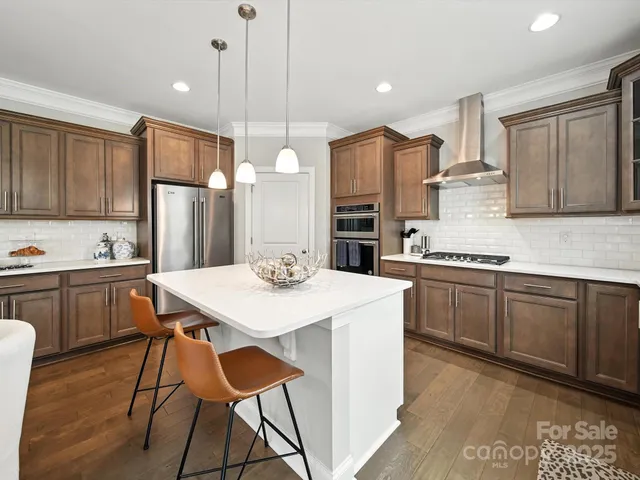 a kitchen with stainless steel appliances a stove a sink a refrigerator a center island and chairs