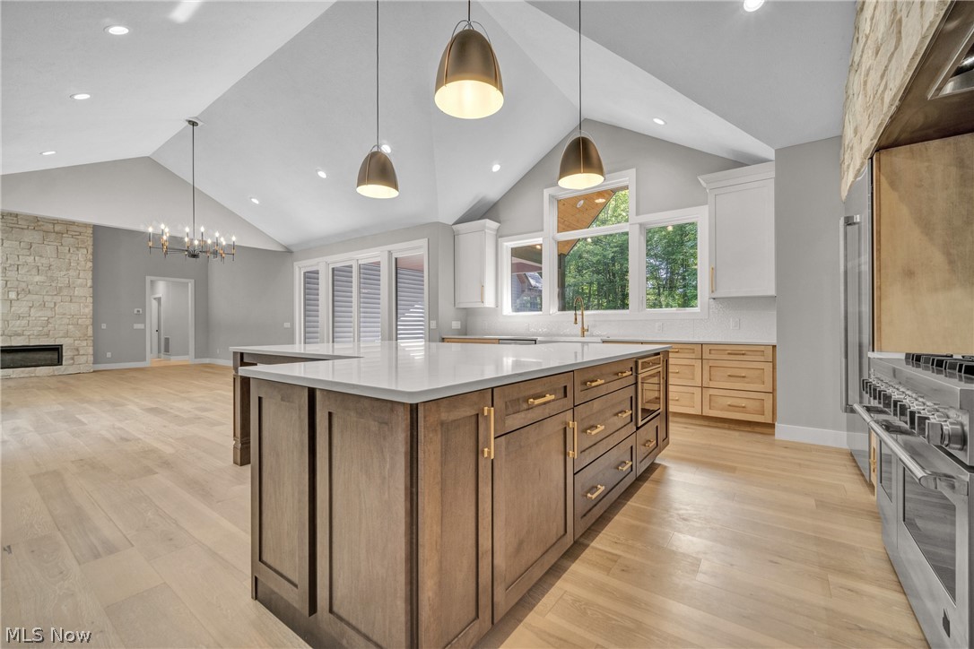 4009 Brainard Road Beachwood, OH 44122 - Photo 20 of 50 Kitchen featuring hanging light fixtures, light wood flooring, a center island, double oven range, and a stone fireplace