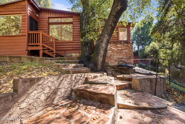 a backyard of a house with large trees and wooden fence