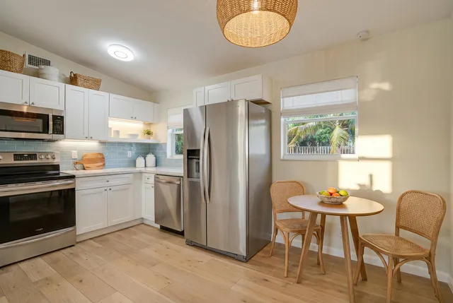 a kitchen with stainless steel appliances granite countertop a refrigerator a stove a microwave oven a sink dishwasher with a dining table and chairs