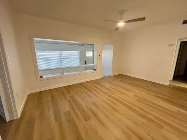 a view of an empty room with wooden floor and a window