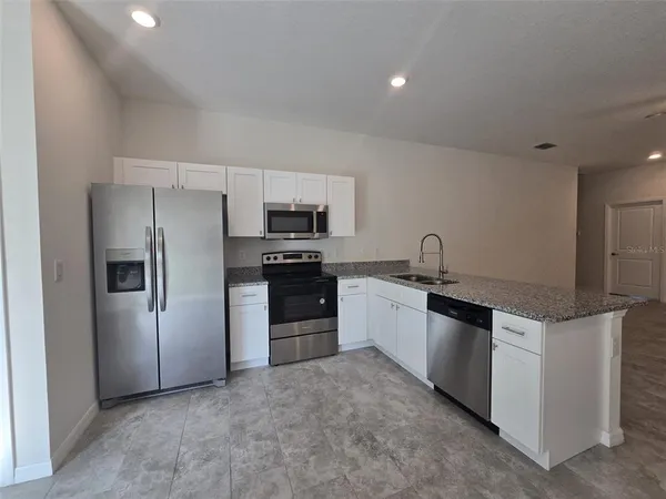 a kitchen with granite countertop a refrigerator and a stove top oven