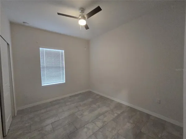 an empty room with a window and a fan