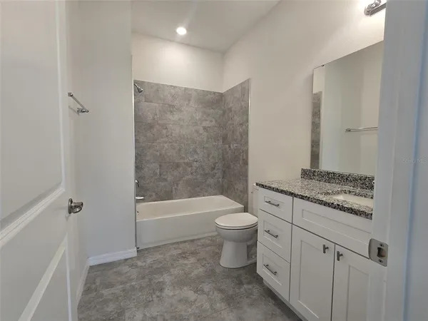 a bathroom with a granite countertop toilet a sink and bathtub