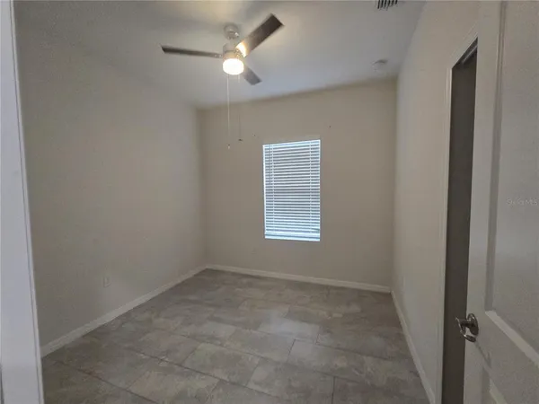 an empty room with a window and a fan