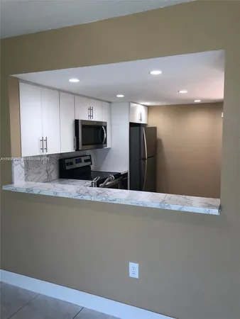 a view of a kitchen with a stove wooden cabinets and a refrigerator
