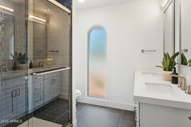 a bedroom with a bed and a potted plant on the dresser