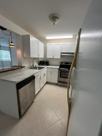 a kitchen with granite countertop a sink stainless steel appliances and cabinets