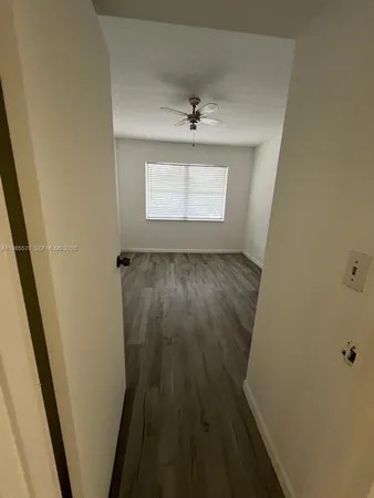 en empty room with wooden floor and fan