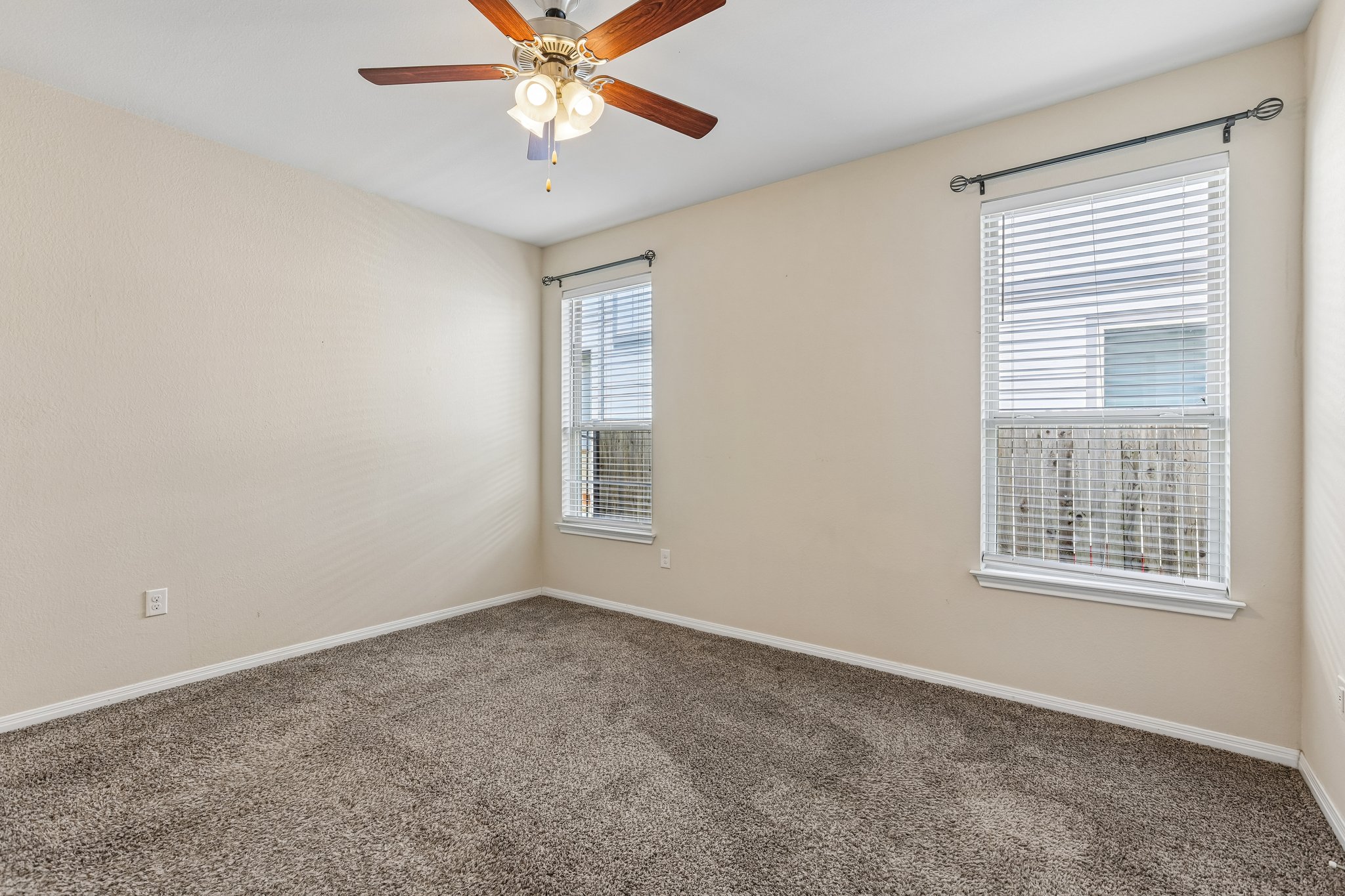 808 Totis Road Austin, TX 78748 - Photo 14 of 40 Carpeted room featuring two windows with horizontal blinds, a ceiling fan with integrated lighting, and neutral-toned walls