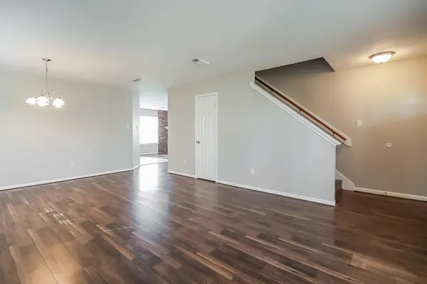 a view of an empty room with wooden floor and staircase