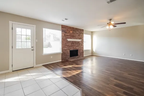 a view of a livingroom with a fireplace a ceiling fan and windows