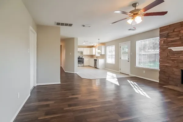 a view of an empty room with window and wooden floor