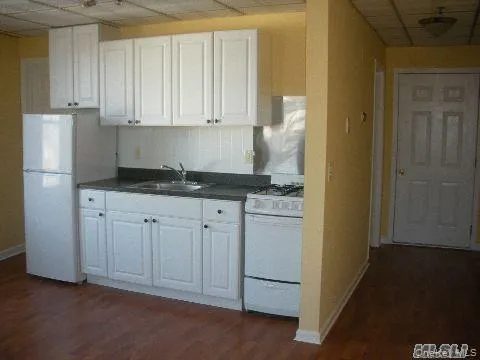 a kitchen with granite countertop white cabinets and refrigerator