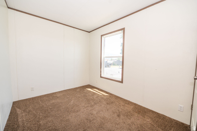 2491 Highway 89, Unit 403 Pleasant View, UT 84404 - Photo 29 of 32 Room featuring soft brown carpet, white wall panels, and contrasting brown trim