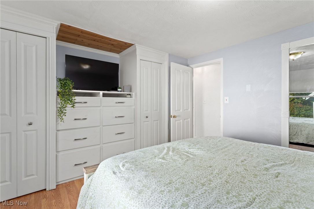 667 High Bridge Road Vermilion, OH 44089 - Photo 18 of 30 Bedroom with multiple closets, wood finished floors, and a textured ceiling