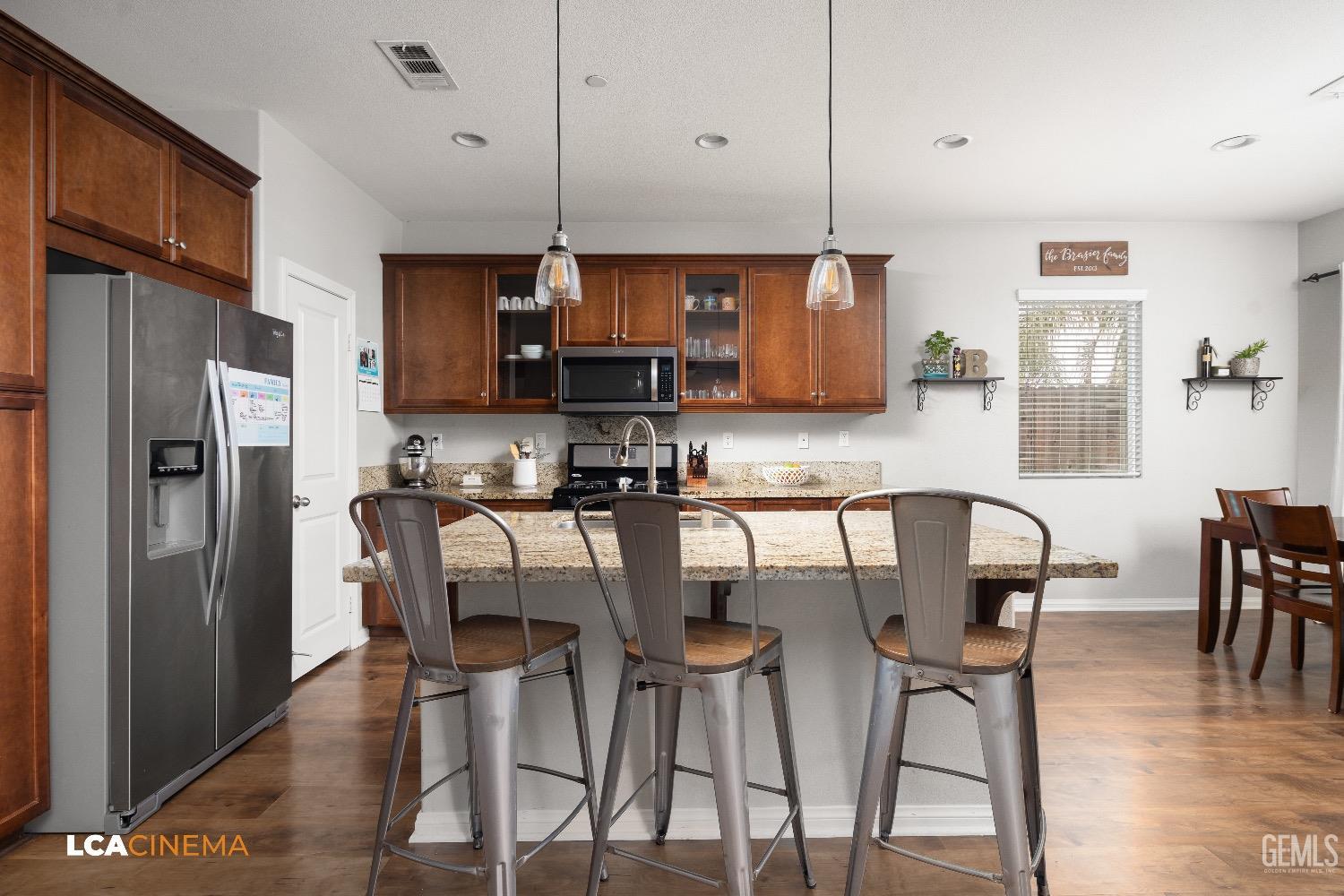 Undisclosed Address Bakersfield, CA 93313 - Photo 11 of 28 a kitchen with stainless steel appliances granite countertop a dining table chairs refrigerator and microwave