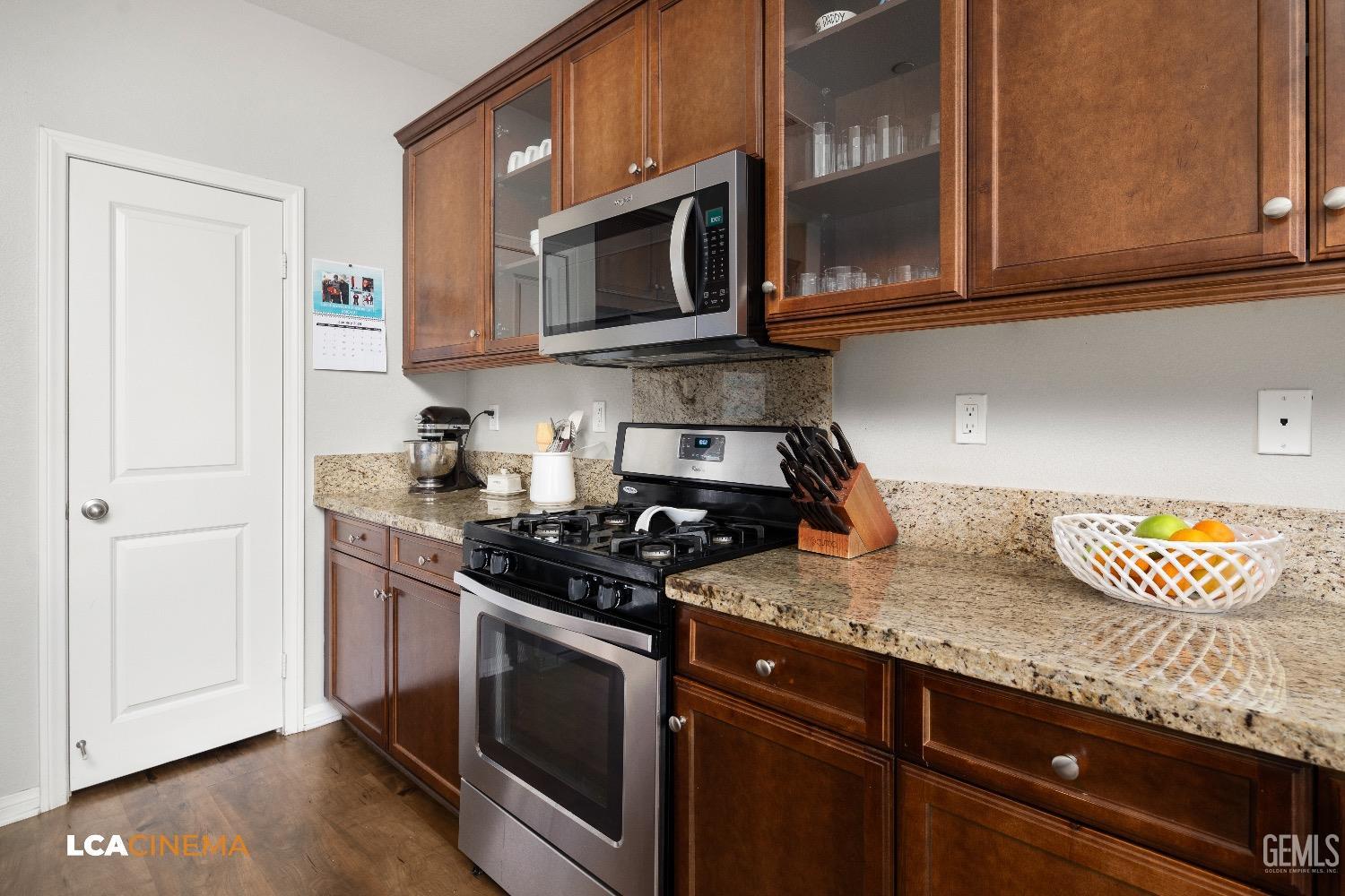 Undisclosed Address Bakersfield, CA 93313 - Photo 14 of 28 a kitchen with granite countertop stainless steel appliances a stove a microwave oven cabinets and a wooden floor