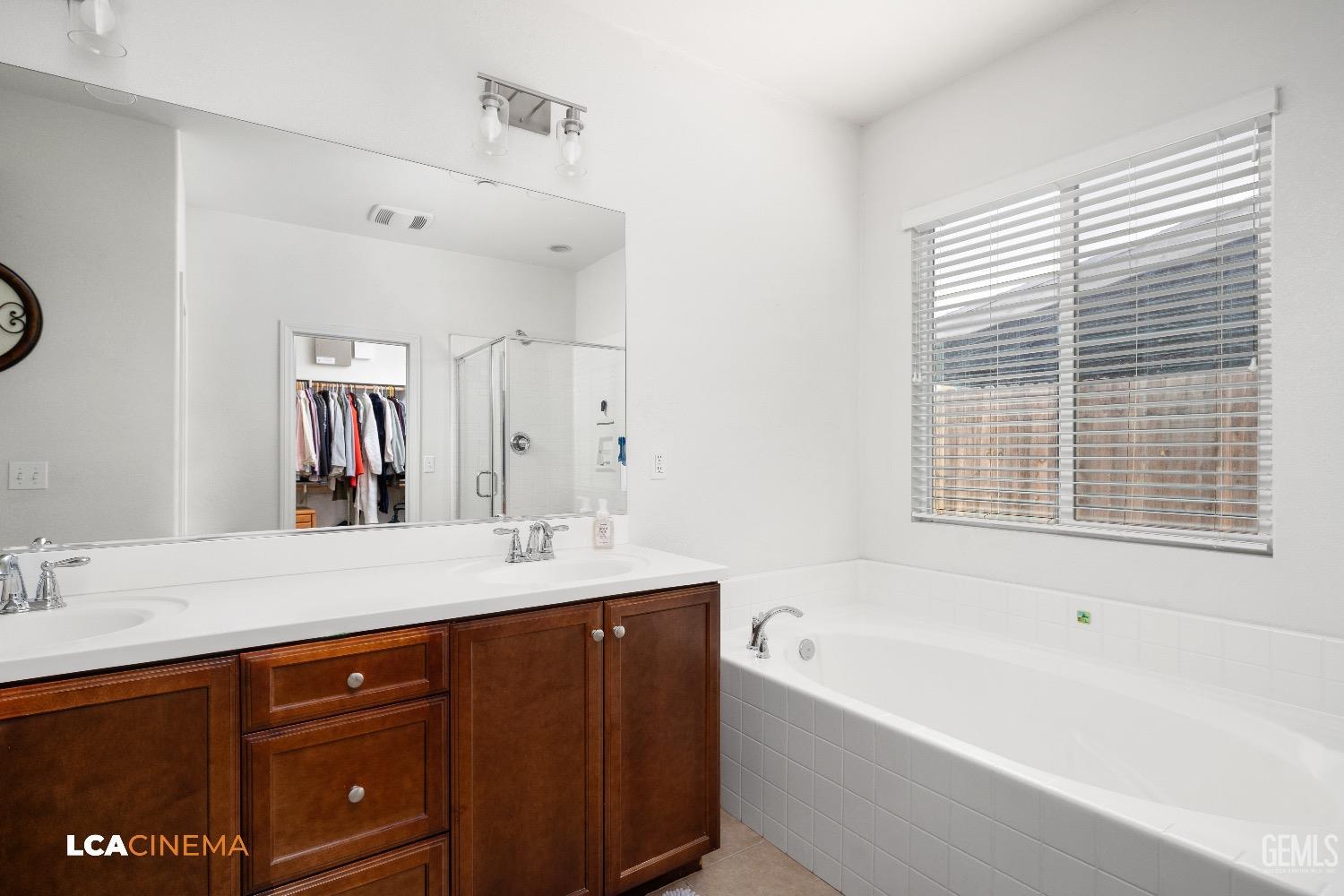 Undisclosed Address Bakersfield, CA 93313 - Photo 17 of 28 a bathroom with a tub a double vanity sink and a large mirror
