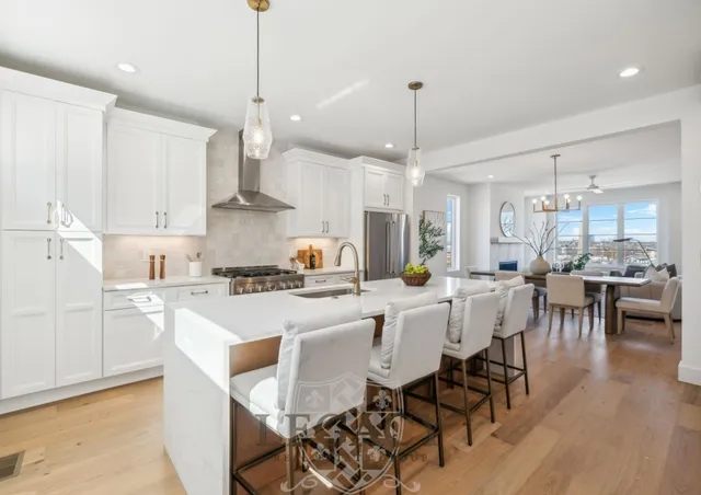 a kitchen with stainless steel appliances a dining table chairs stove and white cabinets