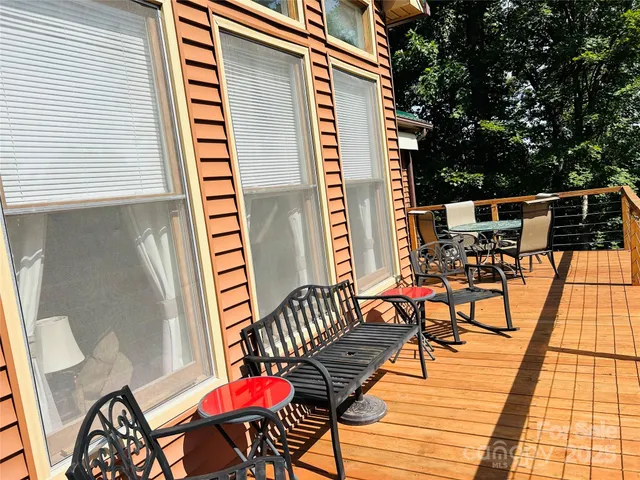 a view of a roof deck with table and chairs a barbeque with wooden floor and fence