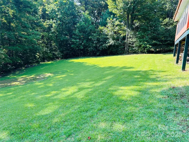 a view of yard with swimming pool and trees in the background