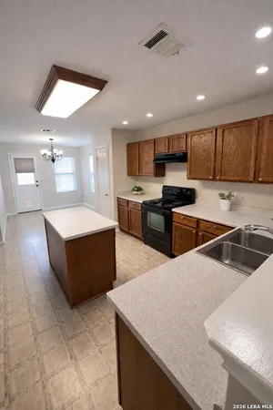 a large kitchen with stainless steel appliances a large counter top a stove a sink a refrigerator and a dining table