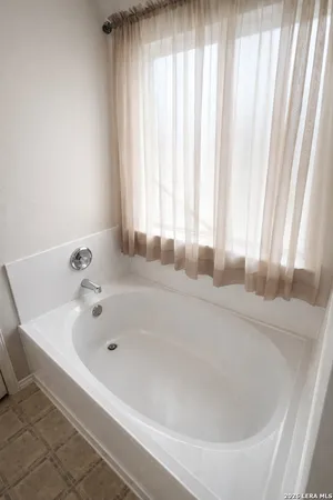 a white bath tub sitting in a bathroom next to a window