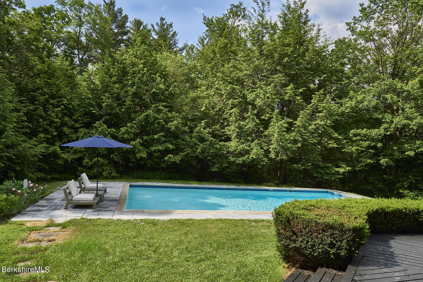 130 Woodmere Road Becket, MA 01223 - Photo 29 of 50 a view of a swimming pool with a table and chairs under an umbrella