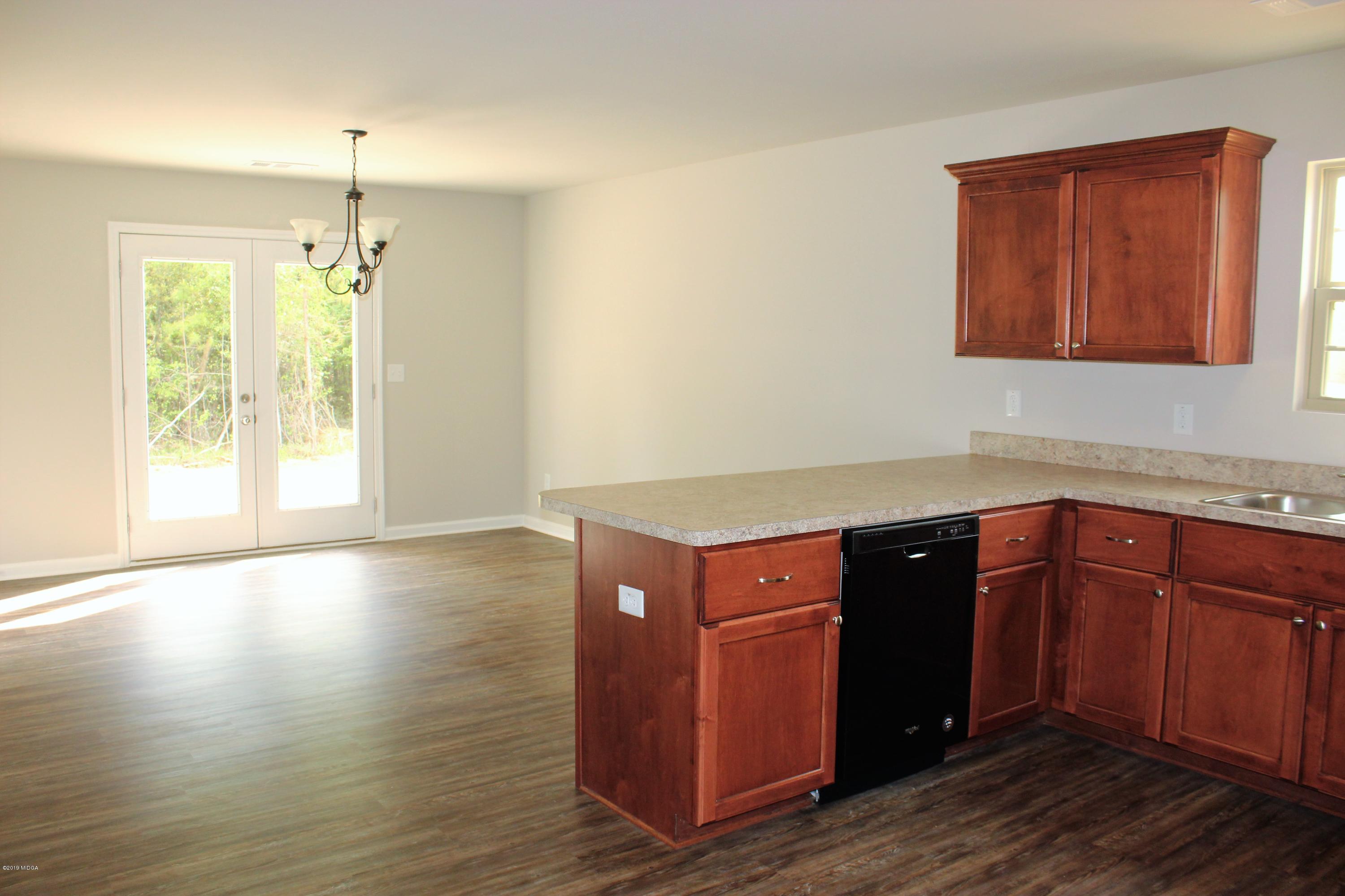805 Weldon Road Forsyth, GA 31029 - Photo 2 of 5 a kitchen with granite countertop wooden cabinets and a wooden floor