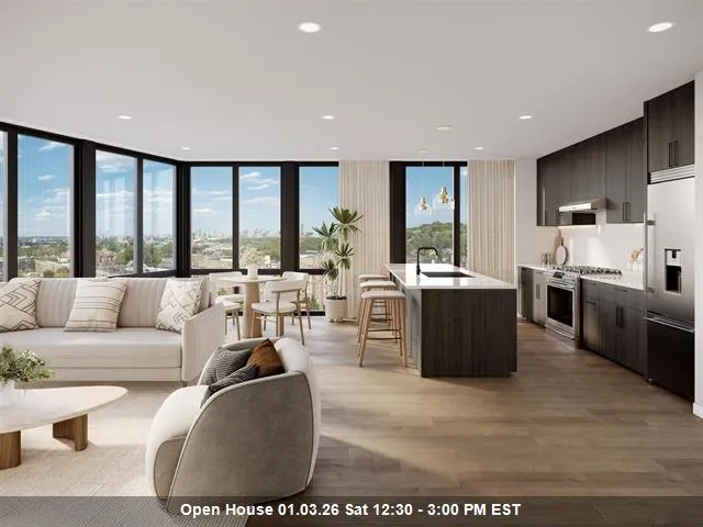 a living room with furniture large windows and kitchen view