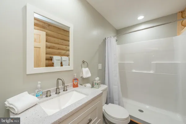 a bathroom with a bathtub shower sink vanity mirror and toilet