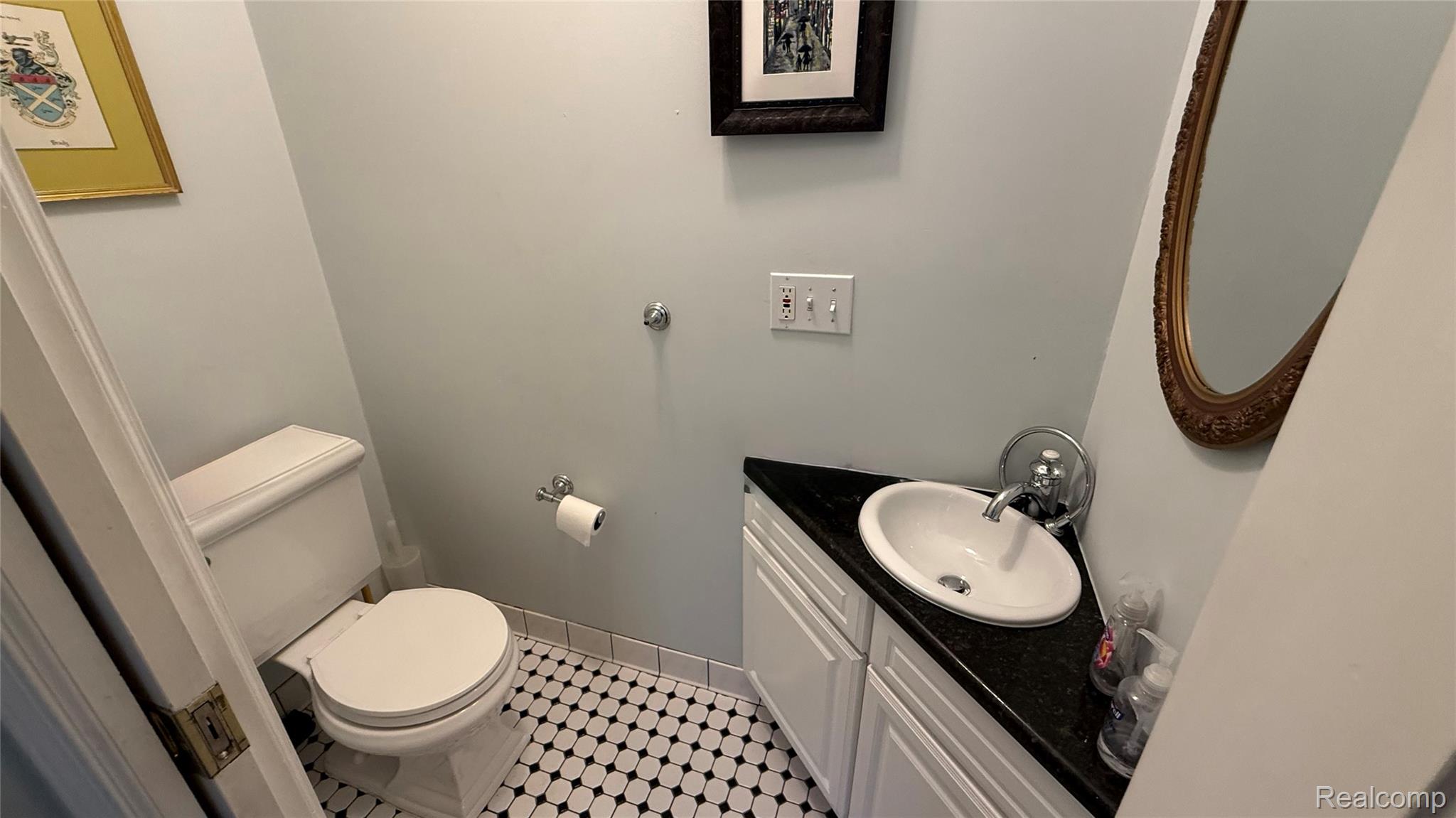 889 Rivard Boulevard Grosse Pointe, MI 48230 - Photo 3 of 18 Powder room featuring a corner vanity with a dark granite countertop, a white oval sink, and a single-handle faucet