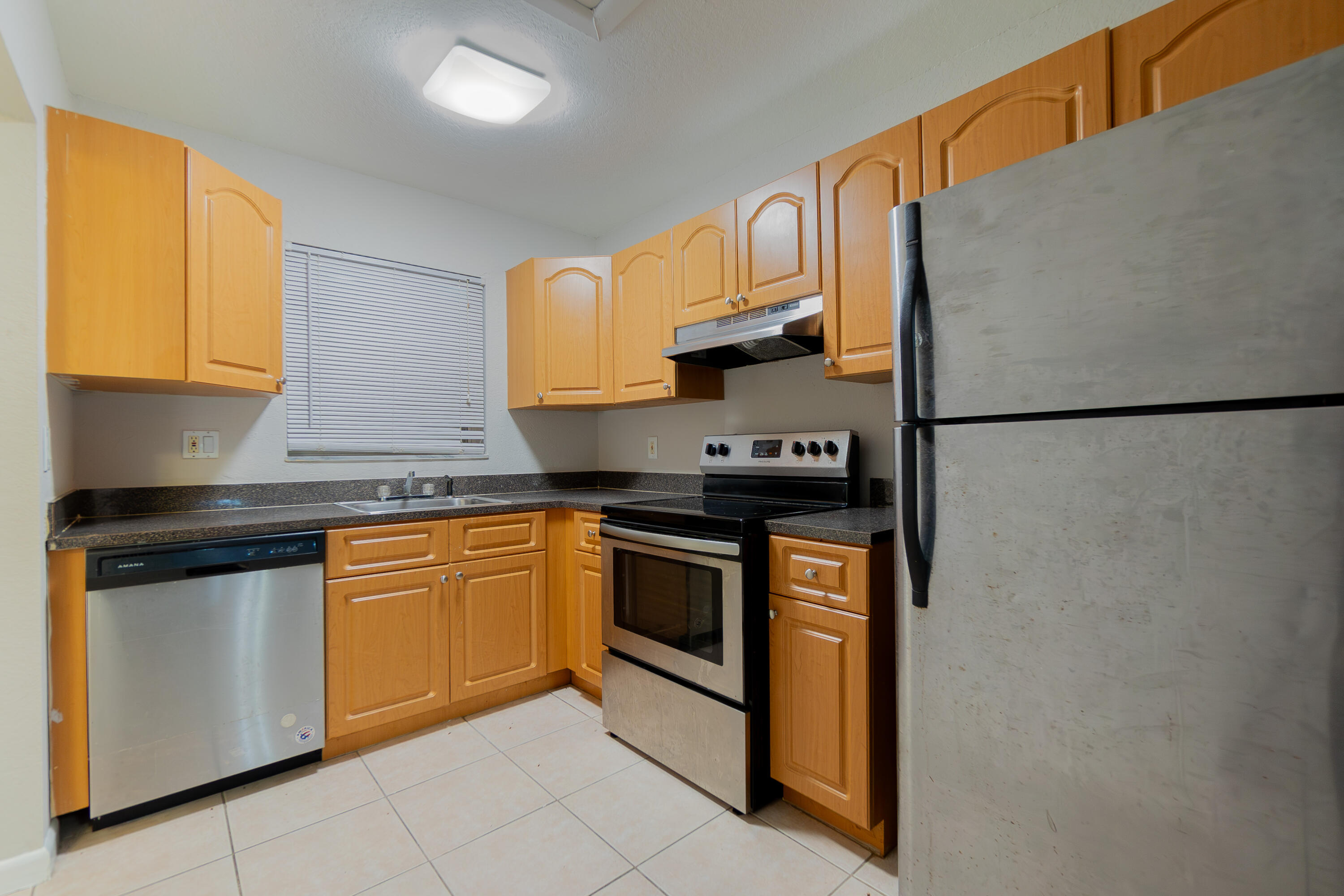 120 Sparrow Drive, Unit 314 Royal Palm Beach, FL 33411 - Photo 4 of 17 a kitchen with stainless steel appliances granite countertop a refrigerator stove a sink and a microwave