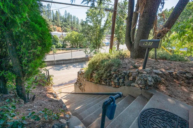 a view of a backyard with table and chairs and a barbeque with a large tree
